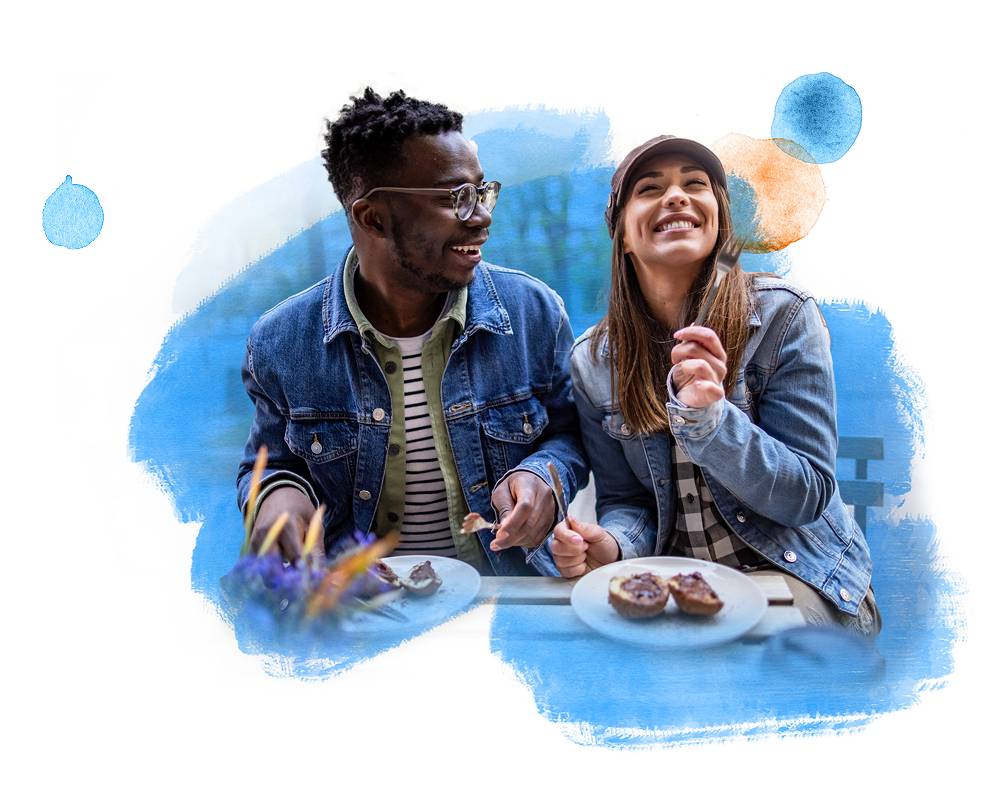 Two people laughing while eating at an outdoor café